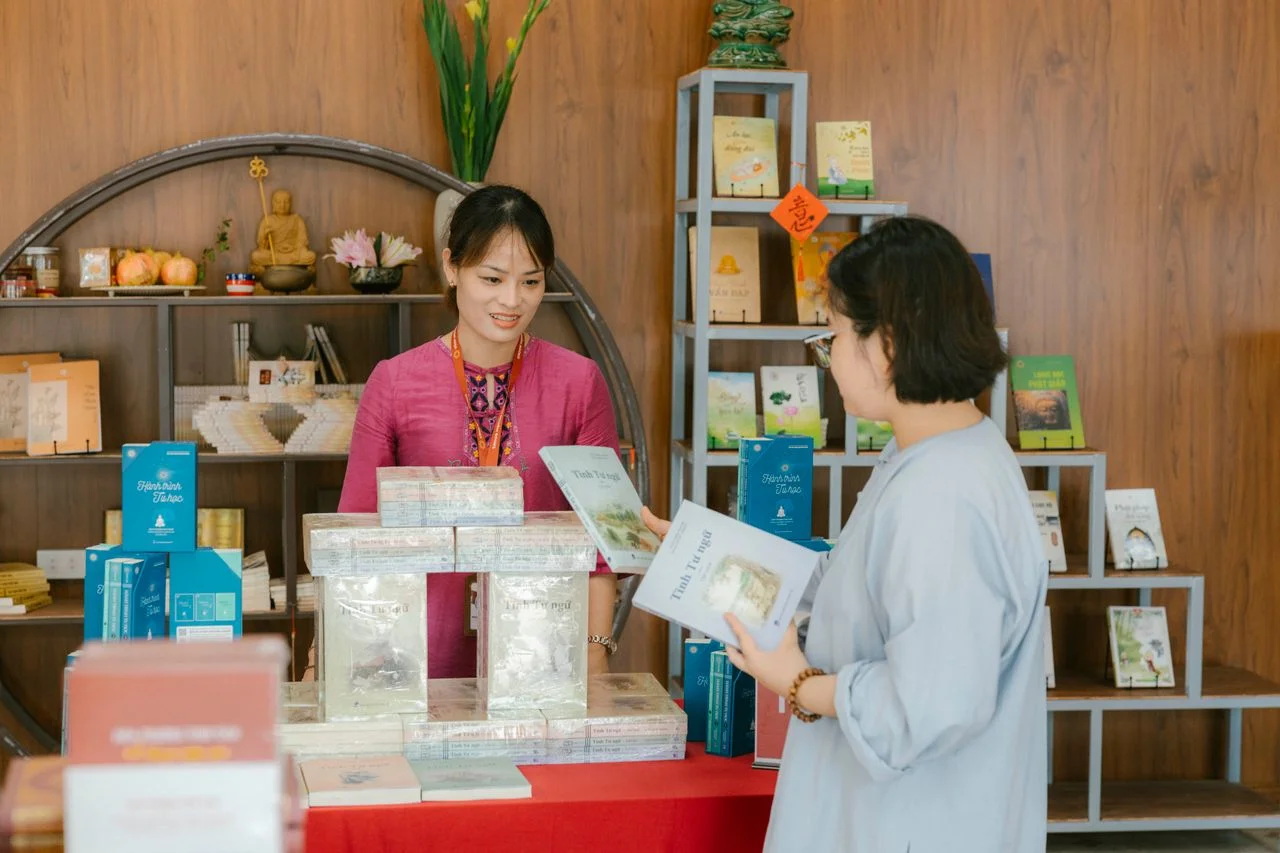two women standing at a table with books